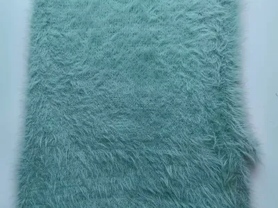 Mintgrüner Kunstfell-Stoff mit langem fluffigem Flor in Nahaufnahme auf weißem Hintergrund