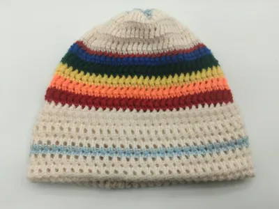 Gestrickte Mütze in Cremefarben mit bunten Streifen in Rot, Orange, Gelb, Grün und Blau sowie offenem Netzmuster am Körper