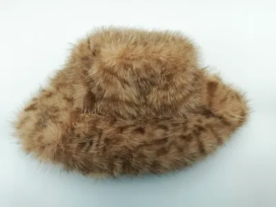 Beige-brauner Kunstfell-Bucket-Hat mit fleckigem Muster und flauschiger Textur auf weißem Hintergrund