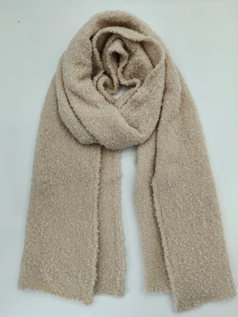 Großformatiger Bouclé-Strickschal in warmem Beige, locker drapiert auf weißem Untergrund