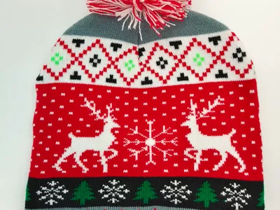 Rote und weiße Weihnachtsmütze im Fair-Isle-Strick mit Rentieren, Schneeflocken, Tannenbäumen und rot-weißem Bommel auf der Spitze