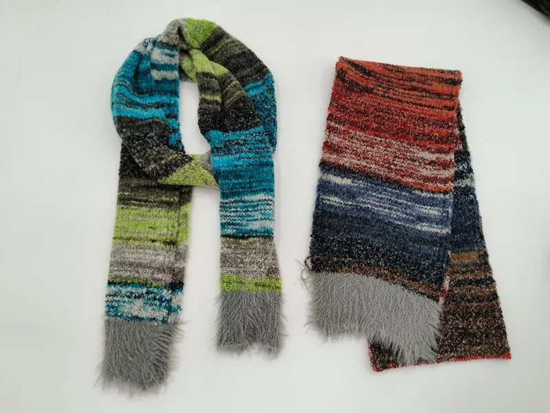Zwei gestreifte Strickscharls mit Kunstfell-Fransenden, einer in Blau-Grün-Grau und einer in Rot-Blau-Braun Tönen, flach ausgelegt