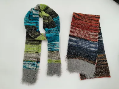 Zwei gestreifte Strickscharls mit Kunstfell-Fransenden, einer in Blau-Grün-Grau und einer in Rot-Blau-Braun Tönen, flach ausgelegt