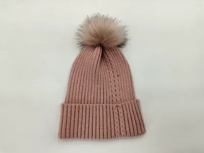 Puderrosa Strickmütze mit großem fluffigem Kunstfell-Pompom, auf weißem Hintergrund fotografiert