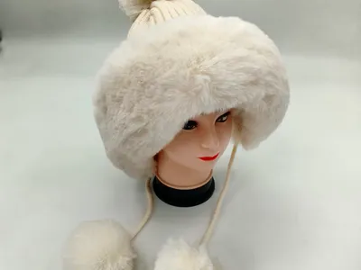 Weißer Kunstfell-Winterhut mit gestricktem Bommel an der Spitze und herabhängenden Pelz-Pompom-Bindebändern auf einer Hutform
