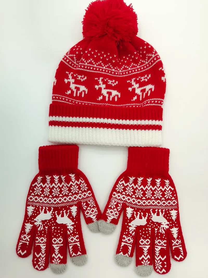 Rot-weiße Fair-Isle-Strickmütze mit Bommel und dazu passende Rentier-Handschuhe auf weißem Hintergrund