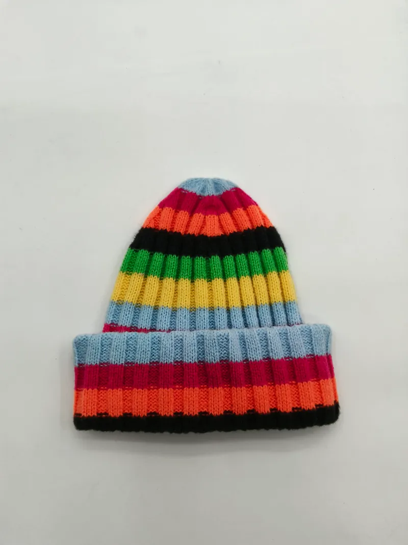 Bunte Strickmütze mit Umschlagrand in leuchtenden Streifen – Blau, Rosa, Orange, Schwarz, Grün und Gelb auf weißem Hintergrund