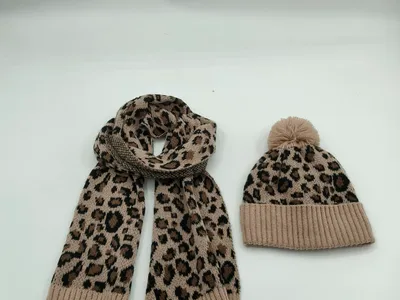 Aufeinander abgestimmter Schal und Bommelmütze mit Leopardenmuster in warmen Braun- und Beigetönen