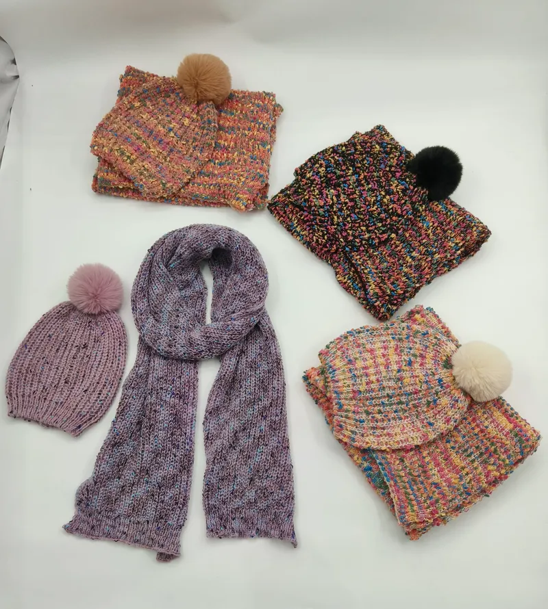 Fünf Strickmützen und Schals in meliertem Buntgarn mit Kunstfell-Pompons in Rosa, Schwarz, Creme und Lila