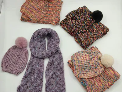 Fünf Strickmützen und Schals in meliertem Buntgarn mit Kunstfell-Pompons in Rosa, Schwarz, Creme und Lila