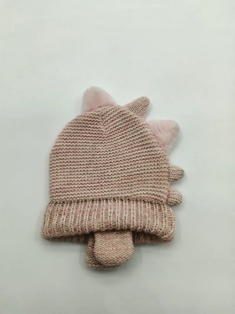 Rosafarbenes Baby-Winterset aus gestrickter Mütze mit flauschigen Einhorn-Pompom-Ohren und dazu passenden Handschuhen, flach auf weißem Hintergrund