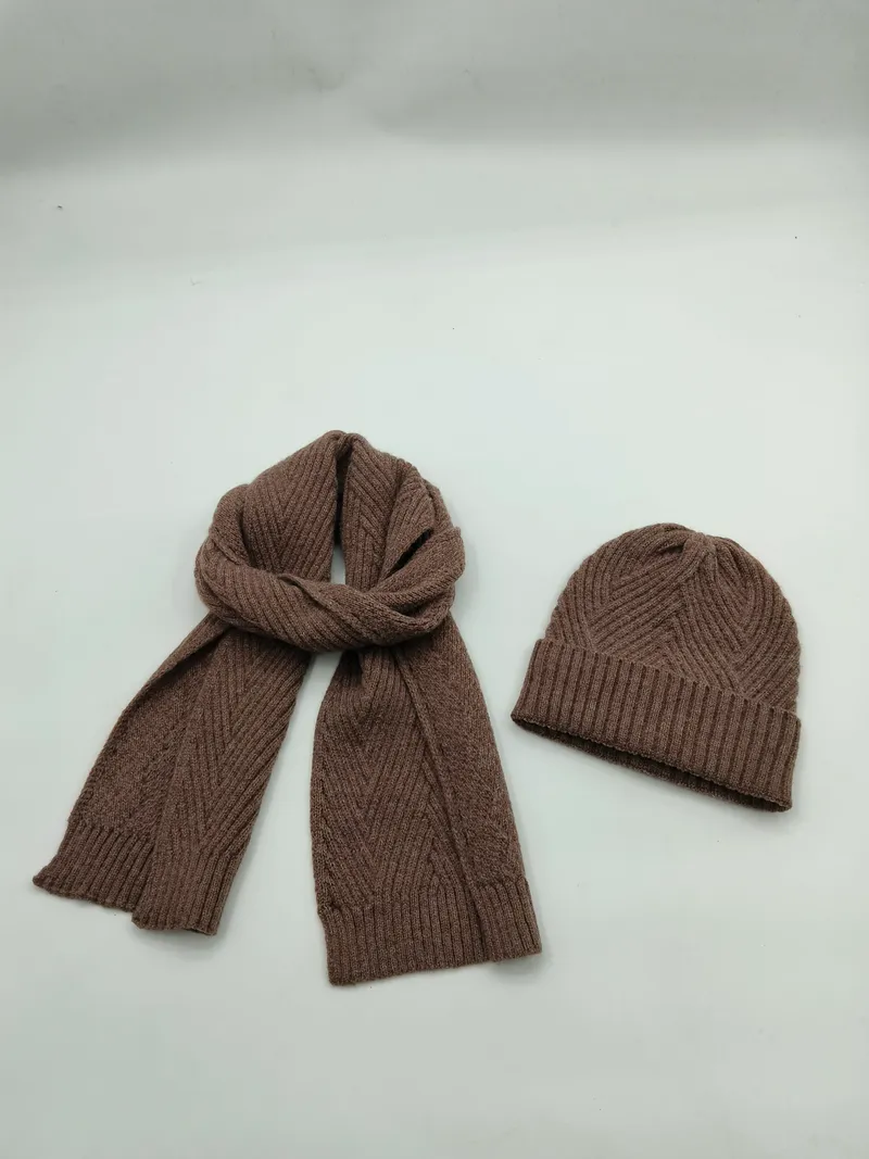 Braunes Rippenstrick-Winterschal und passende Strickmütze mit Zickzack-Textur auf weißem Hintergrund