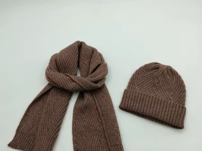 Braunes Rippenstrick-Winterschal und passende Strickmütze mit Zickzack-Textur auf weißem Hintergrund
