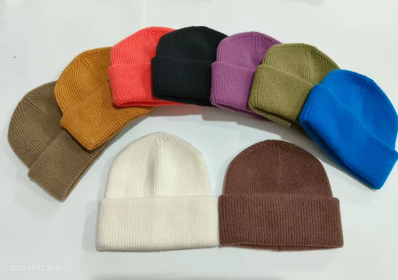 Kollektion aus 10 gerippten Strickmützen mit Umschlagbündchen in verschiedenen Farben wie Weiß, Schwarz, Rot, Blau, Lila, Olive, Braun und Kamel auf weißem Hintergrund