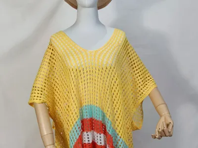Schaufensterpuppe mit gelbem Häkel-Strandponcho und farbigen Streifen in Türkis, Orange, Weiß und Blau am Saum sowie beigem Bucket Hat