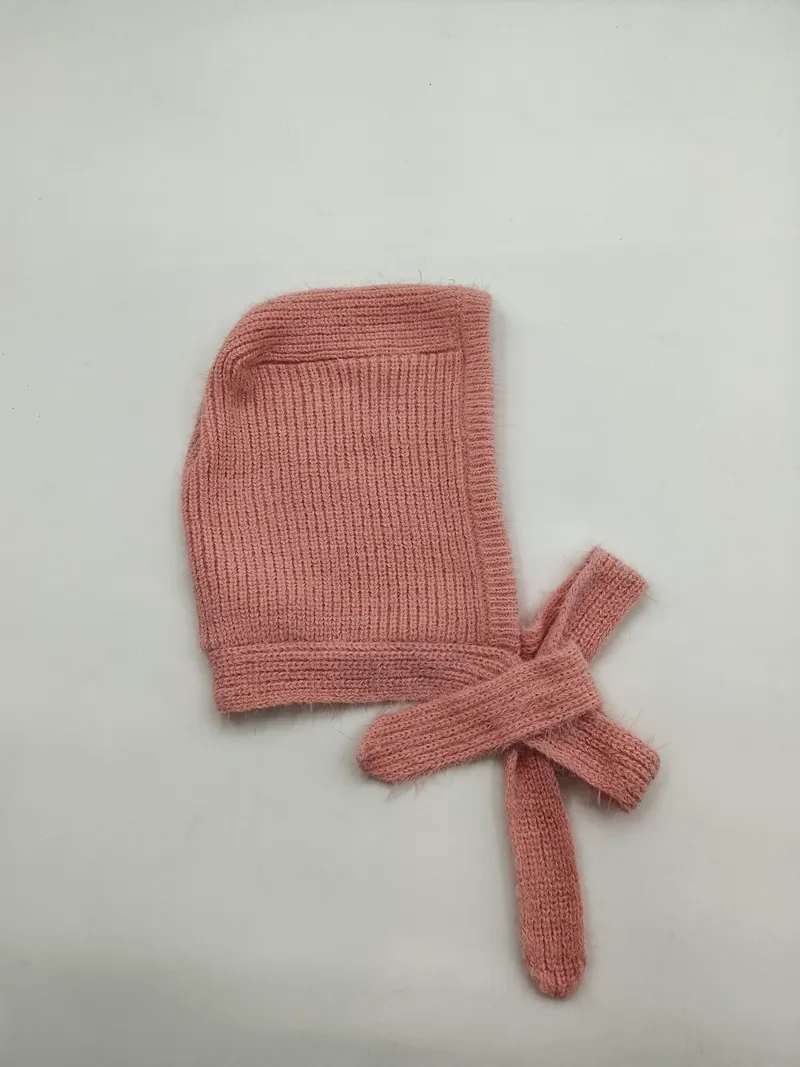 Weiche rosa Rippenstrick-Babyhaube mit langen Bindebändern, flach auf weißem Hintergrund