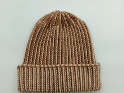Gemütliche Strickmütze in warmen Erdtönen Camel und Creme mit breitem Umschlag, Flachaufnahme auf weißem Hintergrund