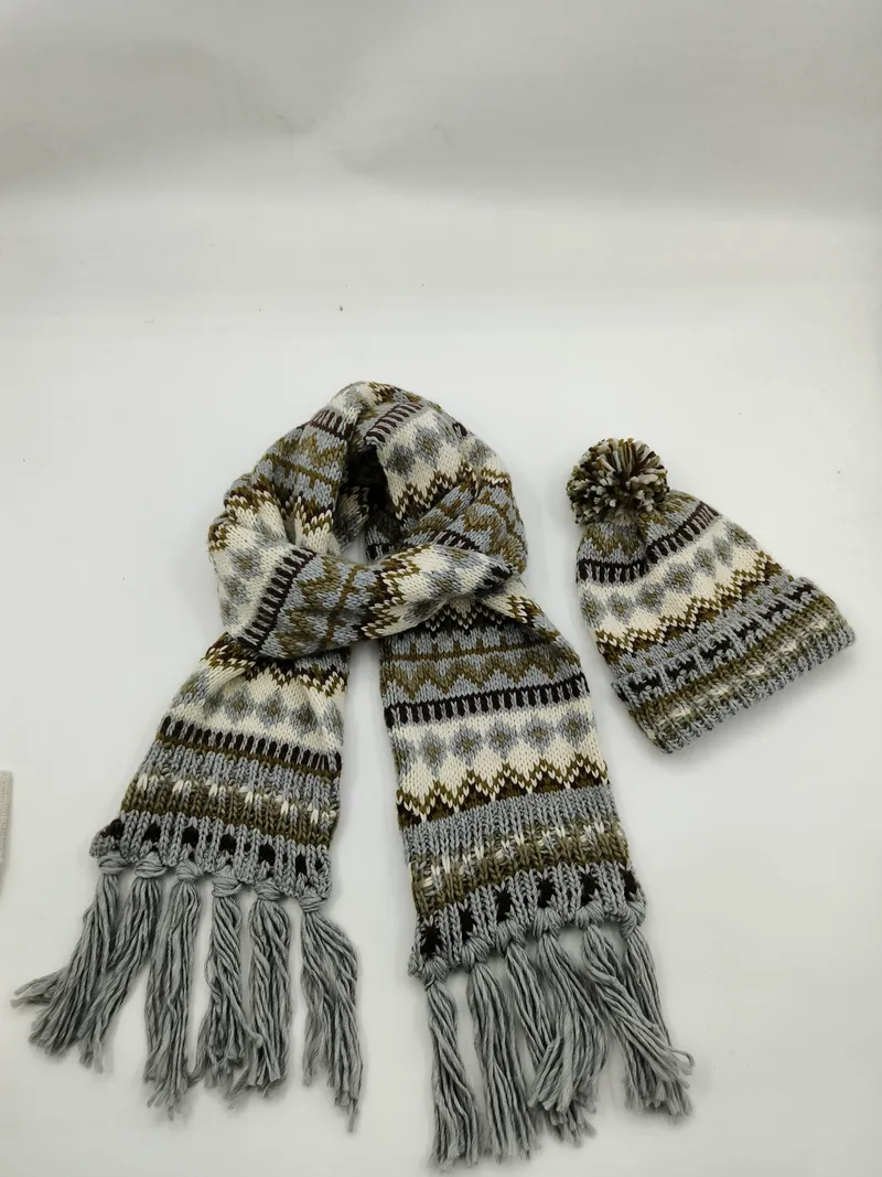Winteraccessoire-Set mit gemustertem Strickschal mit Fransenden und passender Pudelmütze in Grau- und Brauntönen, Produktfoto