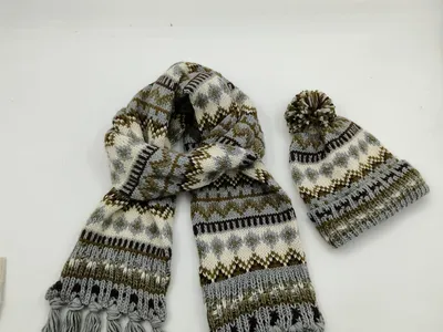 Winteraccessoire-Set mit gemustertem Strickschal mit Fransenden und passender Pudelmütze in Grau- und Brauntönen, Produktfoto