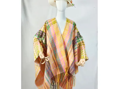 Schaufensterpuppe mit farbenfrohem Chevron-Muster-Umhang in Rosa, Gelb und Grün mit langen Fransenenden und weißem Sonnenhut