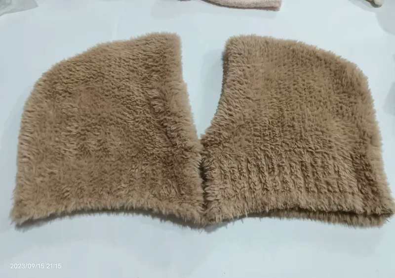 Beiger Kunstfell-Kragenschal in V-Form flach auf weißer Fläche liegend, fluffige Langhaarstruktur sichtbar