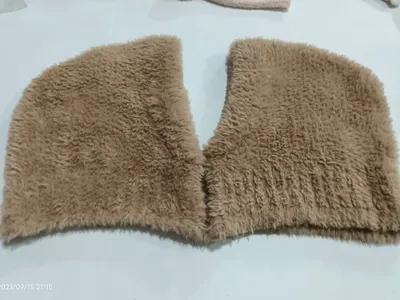 Beiger Kunstfell-Kragenschal in V-Form flach auf weißer Fläche liegend, fluffige Langhaarstruktur sichtbar