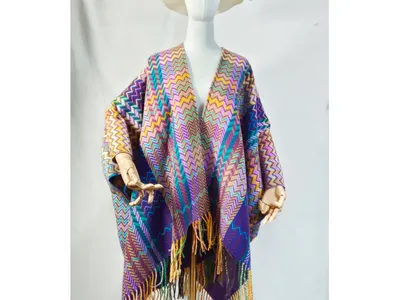 Schaufensterpuppe in farbigem Webponcho mit Chevron-Muster, überlangen Fransenenden und breitem Sonnenhut, Studiofoto