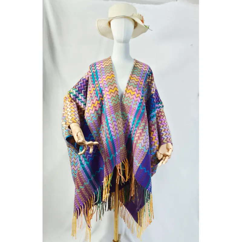 Schaufensterpuppe in farbigem Webponcho mit Chevron-Muster, überlangen Fransenenden und breitem Sonnenhut, Studiofoto