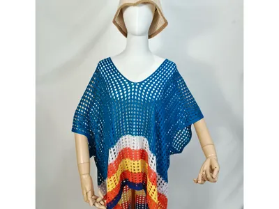 Schaufensterpuppe trägt Häkel-Strandponcho mit blauen, orangenen und gelben Streifen im offenen Netzmuster und Sonnenhut