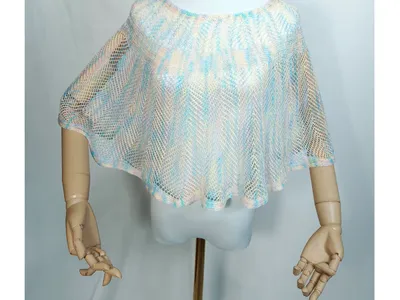 Weiße Schaufensterpuppe mit halbtransparentem Netzponcho in zarten Pastelltönen Hellblau, Pfirsich und Elfenbein, locker drapiert
