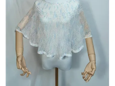 Weiß-blauer Häkelponcho mit offenem Webmuster auf Schaufensterpuppe mit Holzarmen, durchscheinende Netzoptik