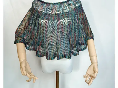 Mehrfarbiger Häkelponcho mit offenem Webmuster auf Schaufensterpuppe mit gegliederten Holzhänden, Regenbogen-Mesh-Stil