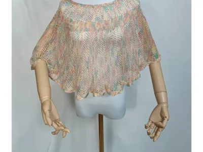 Pastellfarbener offenmaschiger Kurz-Poncho auf Schaufensterpuppe mit Holzarmen, farbenfrohe Häkeloptik in Rosa, Mint und Gelb