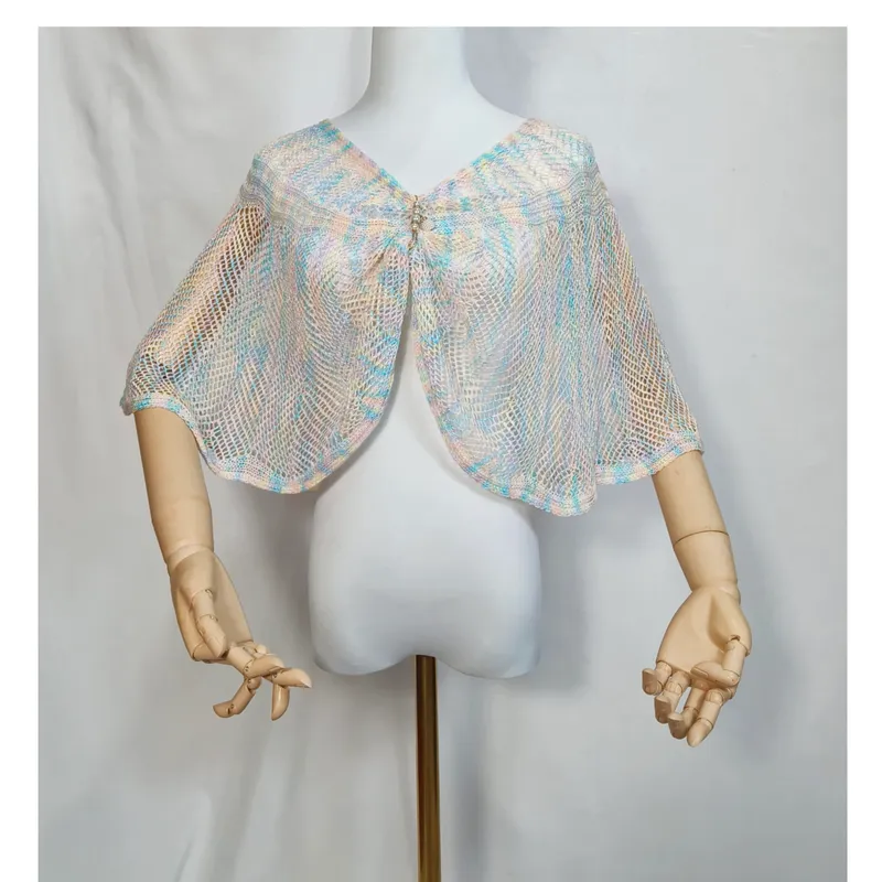 Offener Strickumhang in zartem Blau, Rosa und Creme mit glitzernder Strassbrosche auf weißer Schneiderpuppe