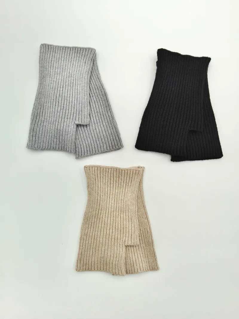 Drei fingerlose Rippstrickhandschuhe in Hellgrau, Schwarz und Beige flach ausgelegt auf weißem Hintergrund