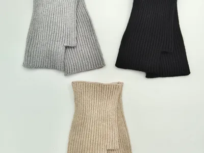 Drei fingerlose Rippstrickhandschuhe in Hellgrau, Schwarz und Beige flach ausgelegt auf weißem Hintergrund