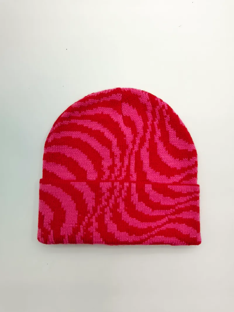 Strickmütze mit Zebra-Streifenmuster in Pink und Rot mit breitem Umschlagrand, Draufsicht auf weißem Hintergrund