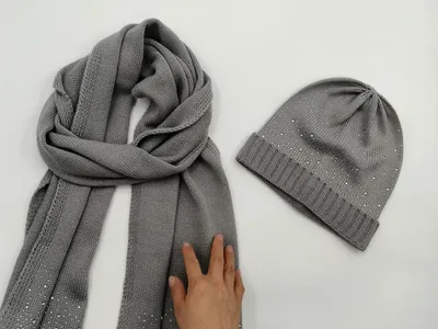 Graues Strickschal und Beanie-Set mit silbernen Strasssteinen auf weißer Fläche flach ausgelegt
