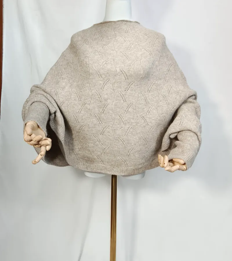 Weiter cremefarbener Ajour-Strickpullover mit ausgestellten Ärmeln und Rautenmuster auf Schneiderpuppe mit Holzkünstlerhänden