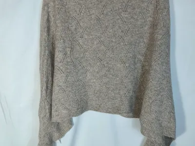 Kurzer Damenpullover in Beige mit offenem Lochstrickmuster, auf Kleiderbügel, lange weite Ärmel mit Rippbündchen