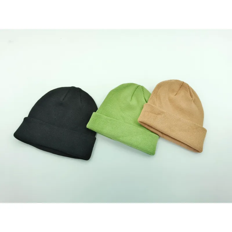Drei schlichte Umschlag-Beanies flach liegend in Schwarz, Olivgrün und Hellbraun auf weißem Untergrund
