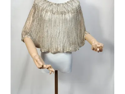 Kurzer Häkelponcho in Beige und Gold auf Schneiderpuppe, Diamant-Mesh-Muster, weite Fledermausärmel, Holzhände sichtbar