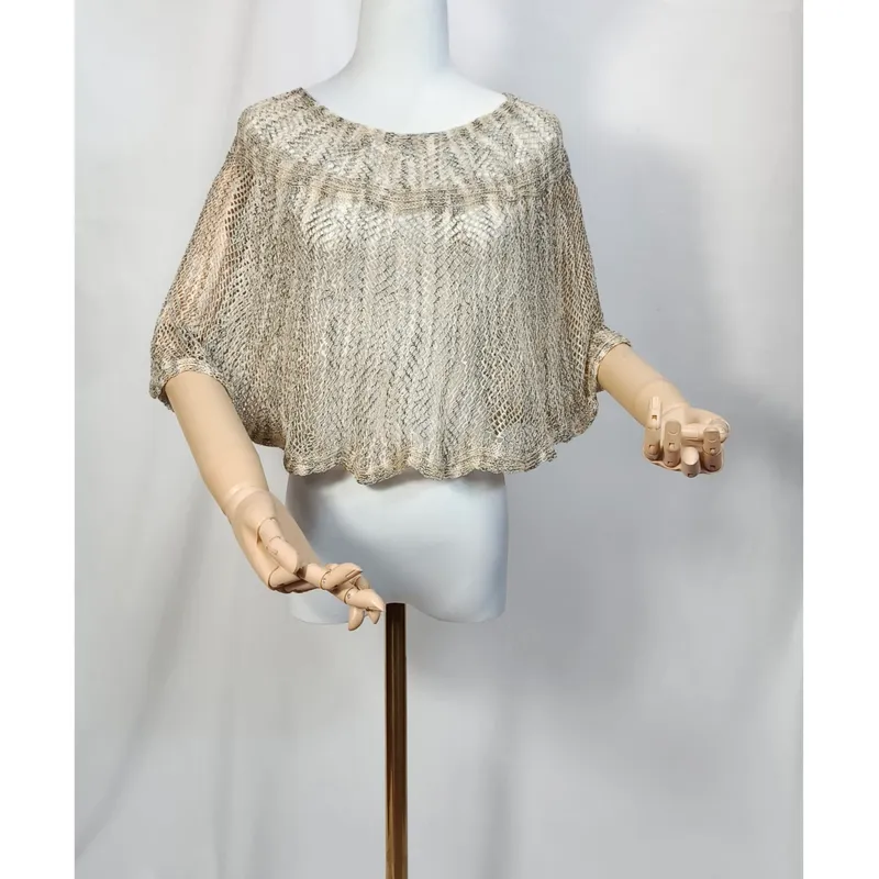 Kurzer Häkelponcho in Beige und Gold auf Schneiderpuppe, Diamant-Mesh-Muster, weite Fledermausärmel, Holzhände sichtbar