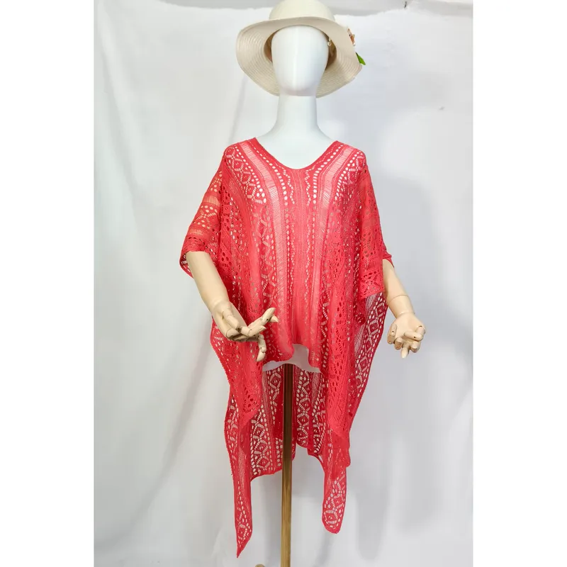 Korallfarbener Häkelponcho im Boho-Stil auf Schaufensterpuppe mit weißem Sonnenhut, luftiges offenes Strickmuster