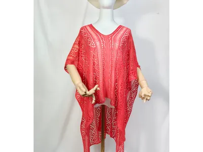Korallfarbener Häkelponcho im Boho-Stil auf Schaufensterpuppe mit weißem Sonnenhut, luftiges offenes Strickmuster
