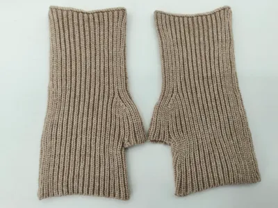 Ein Paar fingerlose Strickhandschuhe in Sandbeige mit Rippenstruktur und Daumenöffnung auf weißem Hintergrund