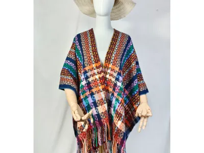 Schaufensterpuppe trägt farbenfrohen Ethno-Poncho mit geometrischem Webmuster und Fransensaum sowie cremefarbenem Schlapphut