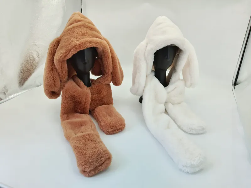 Zwei Kunstpelz-Kapuzenscgals mit langen Hasenohren auf Schaufensterpuppen, in Kamelbraun und Naturweiß auf hellem Untergrund