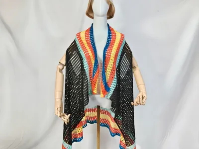 Schwarze offene Häkelweste mit bunter Streifenborte in Blau, Orange, Gelb und Mint auf Schneiderpuppe mit Beige-Hut