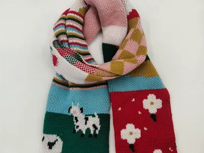 Farbenfroher Strickschal mit Schafs-Motiven, Blumenfeldern, Streifen und Patchwork-Segmenten in Rot, Grün, Blau und Pink